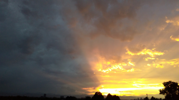 An image of dark clouds with a beautiful sunset shining through the clouds behind it. This image represents learning to release the need to control the storm so we can enjoy the fullness of life.